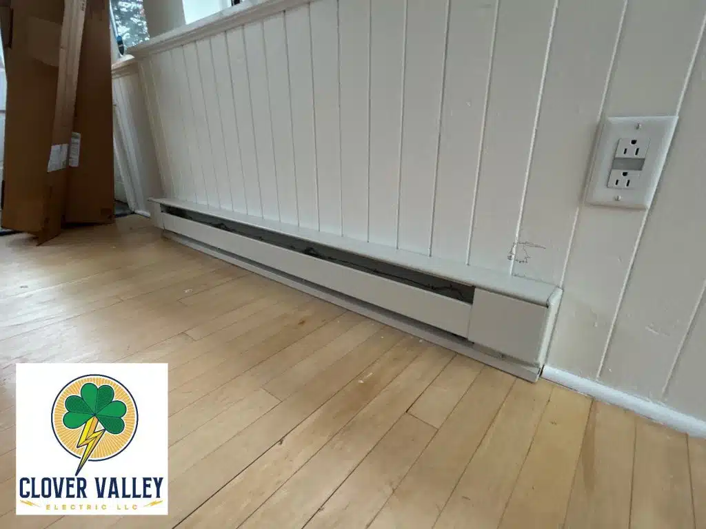 Picture of an electrical baseboard heater along a wall.